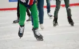 The legs of skaters on an ice rink.