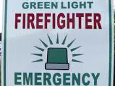 Sign panel reading: yield to flashing green light. Firefighter. Emergency response.