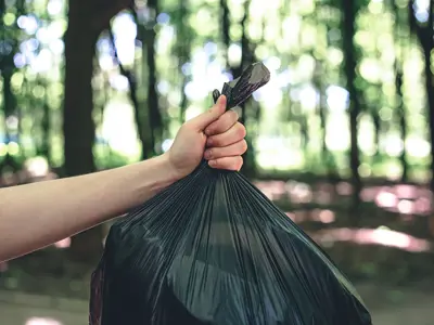 A hand holds a bag of garbage.