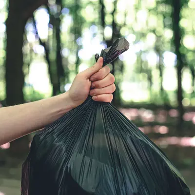 A hand holds a bag of garbage.